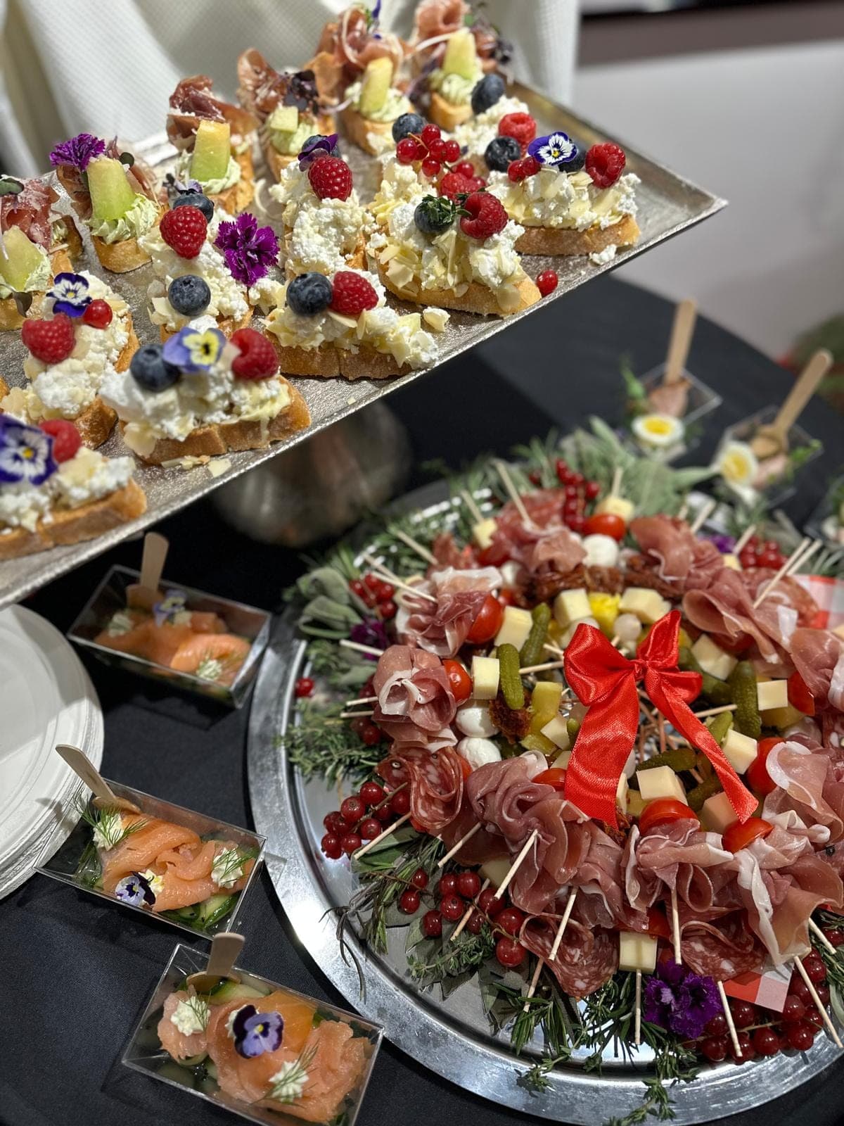 Charcuterie věnec s prosciuttem, sýry a rybízem, uprostřed červená mašle